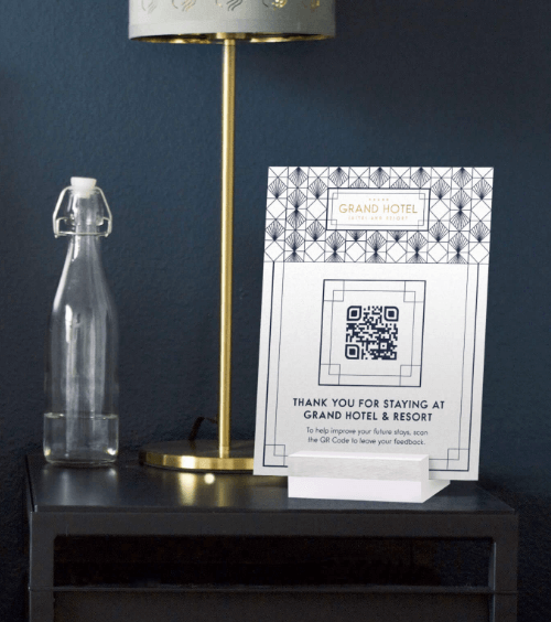 Tischaufsteller in einem Hotelzimmer mit einem QR Code, der ein Feedback-Formular für Gäste verlinkt.